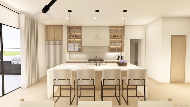 kitchen featuring sink, a breakfast bar, a kitchen island with sink, decorative backsplash, and decorative light fixtures