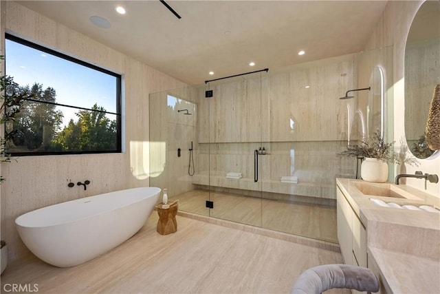 bathroom with independent shower and bath, tile walls, and vanity