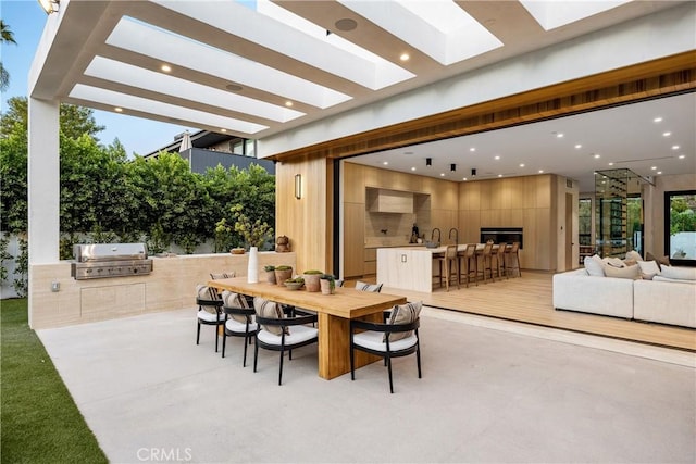 view of patio featuring a bar, an outdoor hangout area, exterior kitchen, and area for grilling