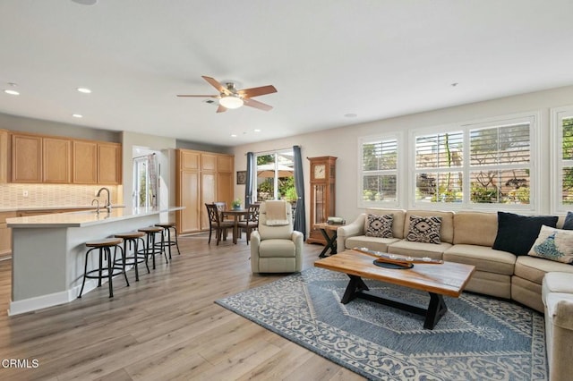 living room with ceiling fan, sink, and light hardwood / wood-style floors