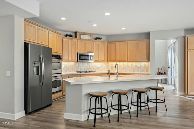 kitchen featuring stainless steel appliances, an island with sink, tasteful backsplash, and sink