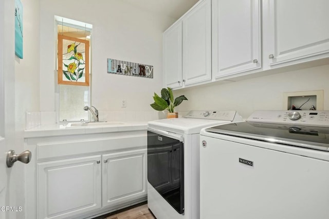 clothes washing area featuring cabinets, sink, and independent washer and dryer