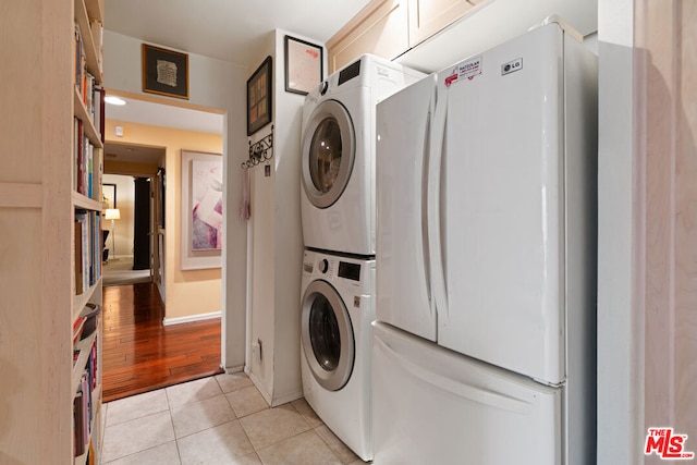 laundry area with stacked washing maching and dryer and light tile patterned floors