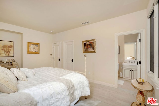 bedroom featuring sink, light wood-type flooring, and connected bathroom