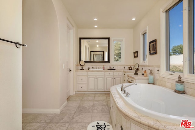 bathroom featuring tiled bath and vanity