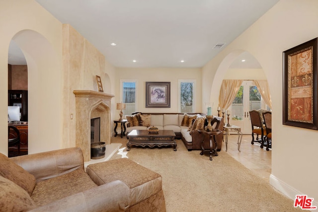 living room with a high end fireplace and light tile patterned flooring