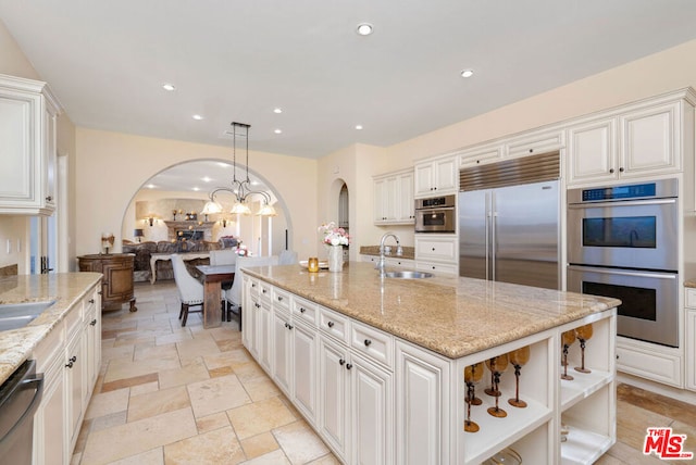 kitchen with decorative light fixtures, light stone counters, appliances with stainless steel finishes, and white cabinetry