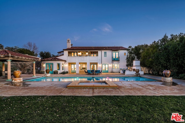 pool at dusk featuring a patio area and a lawn