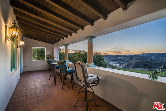 patio terrace at dusk featuring a balcony and a mountain view