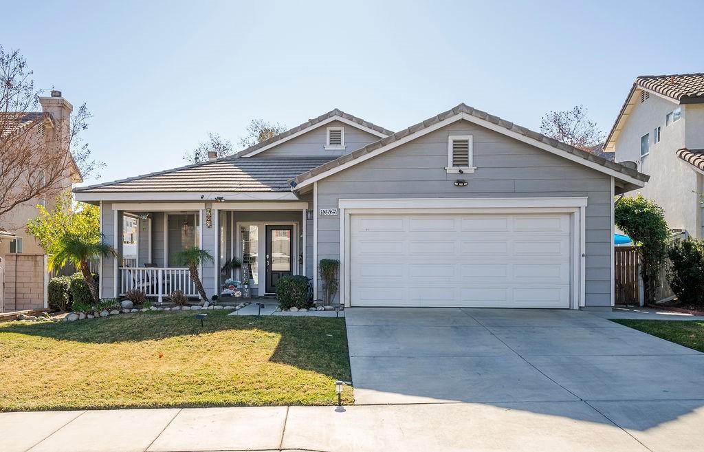 view of front of property featuring covered porch, a front yard, and a garage