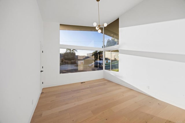 spare room with lofted ceiling, hardwood / wood-style floors, and plenty of natural light