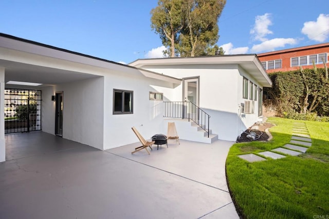 rear view of property with a yard, a patio, and an outdoor fire pit