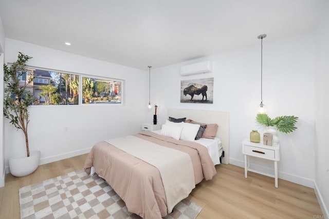 bedroom with light hardwood / wood-style flooring and a wall unit AC