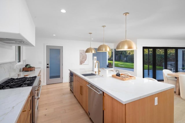 kitchen with stainless steel appliances, a large island, sink, and light stone counters