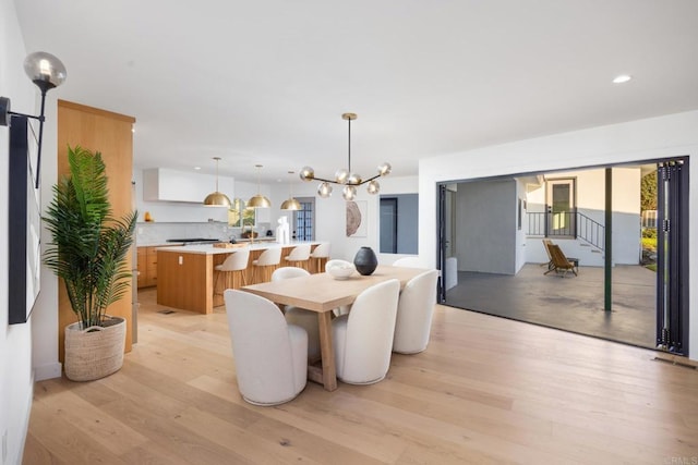 dining area with light hardwood / wood-style flooring and a notable chandelier