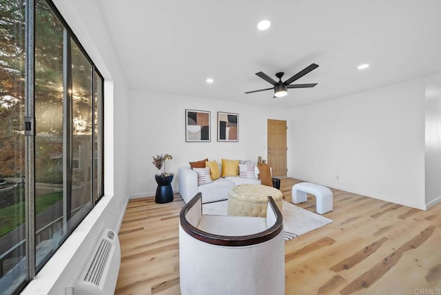 living area with ceiling fan, light wood-type flooring, and plenty of natural light