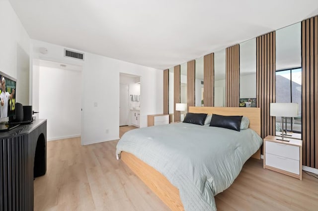 bedroom featuring ensuite bathroom and light hardwood / wood-style floors