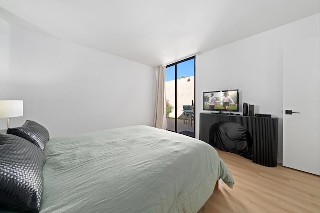 bedroom with hardwood / wood-style flooring and expansive windows