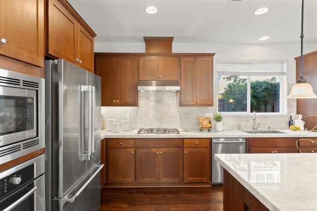 kitchen with hanging light fixtures, dark hardwood / wood-style flooring, sink, backsplash, and stainless steel appliances