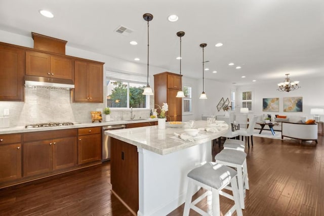 kitchen featuring a kitchen breakfast bar, decorative light fixtures, light stone countertops, a kitchen island, and stainless steel appliances