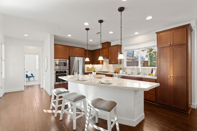 kitchen featuring pendant lighting, stainless steel appliances, a center island, and a breakfast bar area