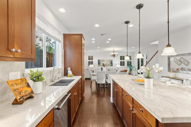 kitchen with light stone countertops, tasteful backsplash, stainless steel dishwasher, sink, and pendant lighting