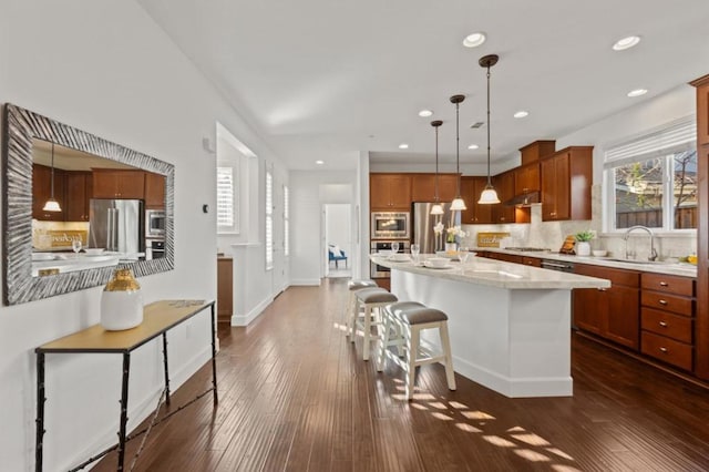 kitchen with sink, pendant lighting, stainless steel appliances, and a kitchen island