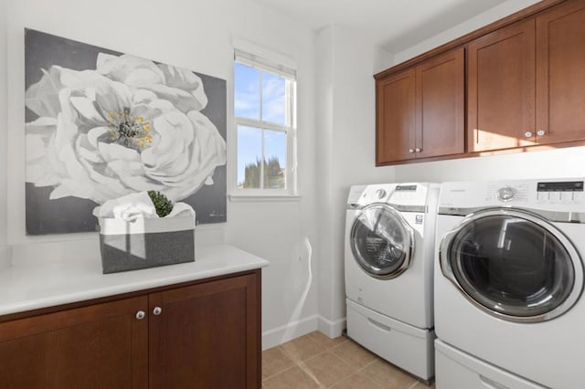 clothes washing area featuring light tile patterned floors, cabinets, and washer and clothes dryer