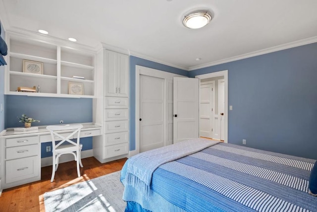 bedroom with built in desk, crown molding, and hardwood / wood-style floors