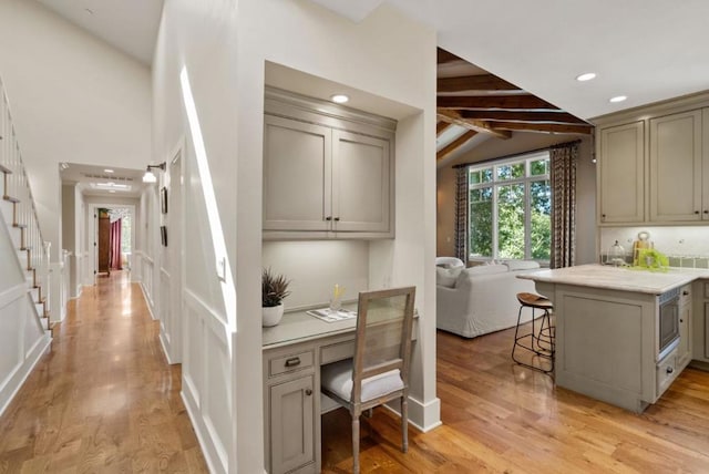 kitchen featuring built in desk, gray cabinetry, a breakfast bar area, and vaulted ceiling with beams