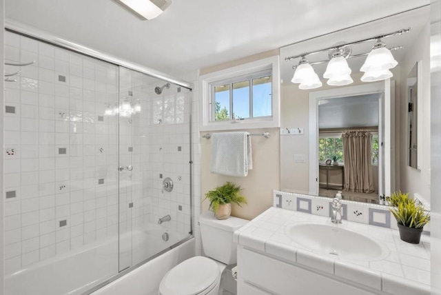 full bathroom with bath / shower combo with glass door, toilet, and vanity