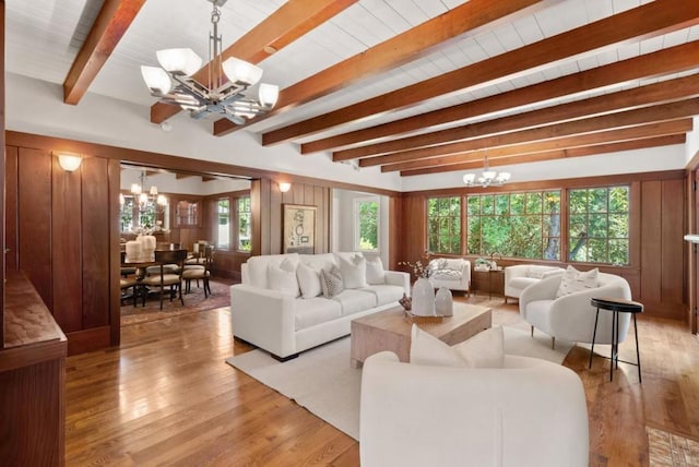 living room with light wood-type flooring, beam ceiling, wood walls, and a notable chandelier