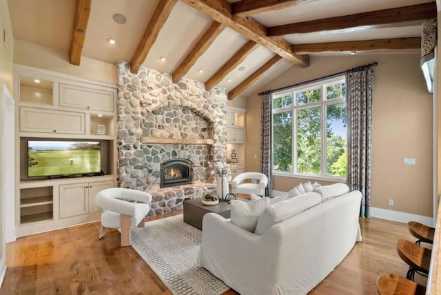 living room with vaulted ceiling with beams, light wood-type flooring, and a fireplace