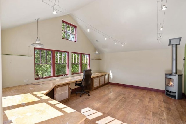 office area featuring vaulted ceiling, track lighting, a wood stove, and wood-type flooring