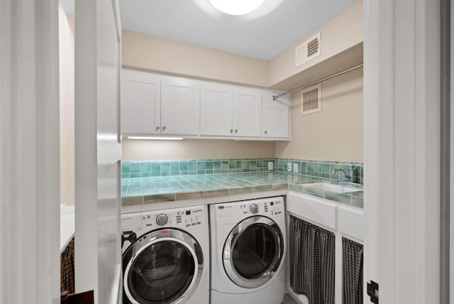 laundry area featuring washer and clothes dryer, sink, and cabinets