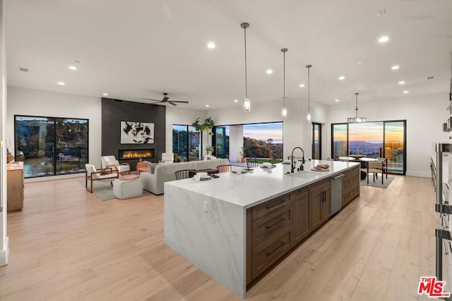 kitchen with a spacious island, pendant lighting, a fireplace, sink, and light stone counters