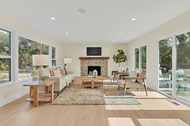 sunroom featuring a stone fireplace and plenty of natural light