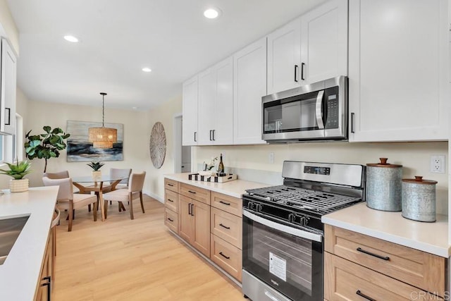 kitchen with pendant lighting, stainless steel appliances, white cabinets, and light brown cabinets