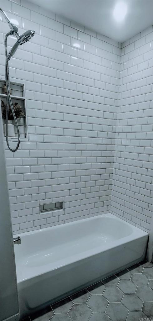 bathroom featuring tile patterned flooring and tiled shower / bath