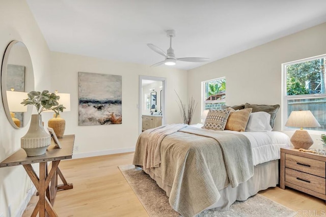 bedroom featuring multiple windows, ceiling fan, connected bathroom, and light wood-type flooring