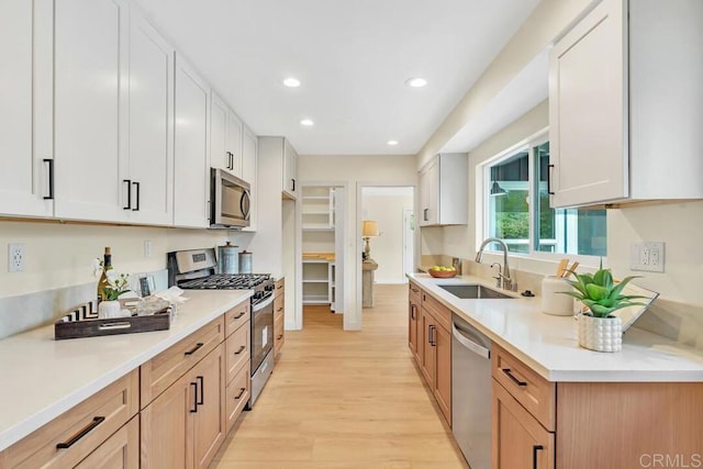 kitchen with white cabinetry, sink, light hardwood / wood-style floors, and appliances with stainless steel finishes