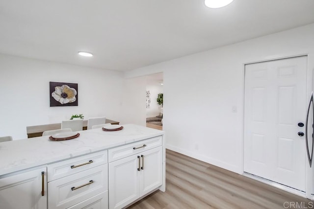 kitchen featuring white cabinetry, light hardwood / wood-style floors, and light stone countertops