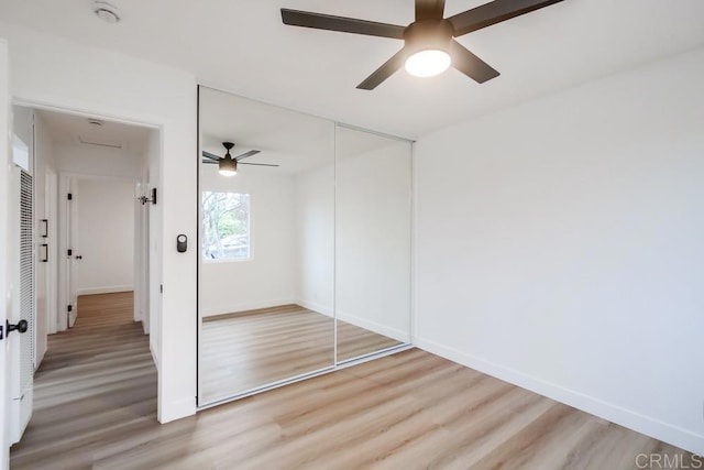 unfurnished bedroom with ceiling fan, a closet, and hardwood / wood-style flooring