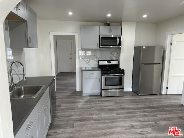 kitchen with wood-type flooring, decorative backsplash, sink, appliances with stainless steel finishes, and gray cabinetry