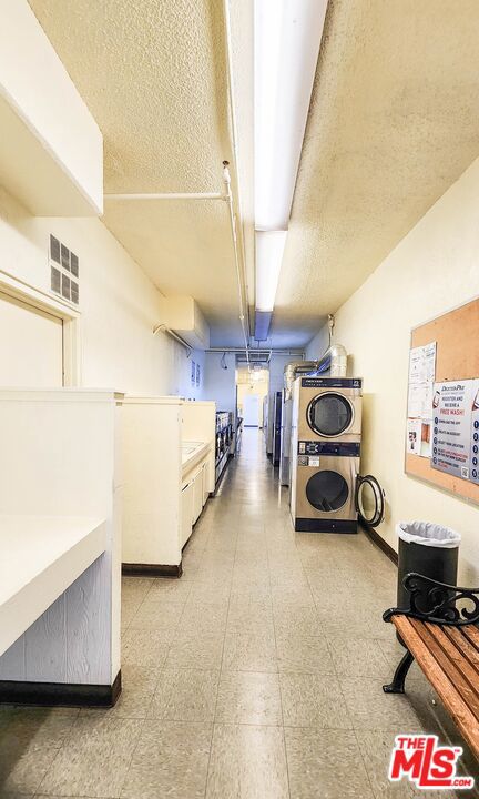 basement with a textured ceiling and stacked washer / dryer