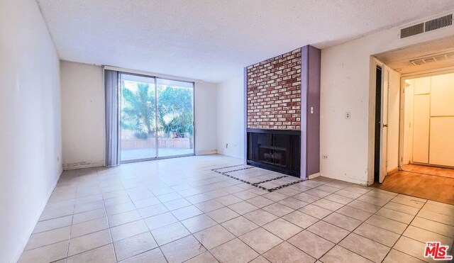 unfurnished living room featuring a textured ceiling, light tile patterned flooring, and a fireplace