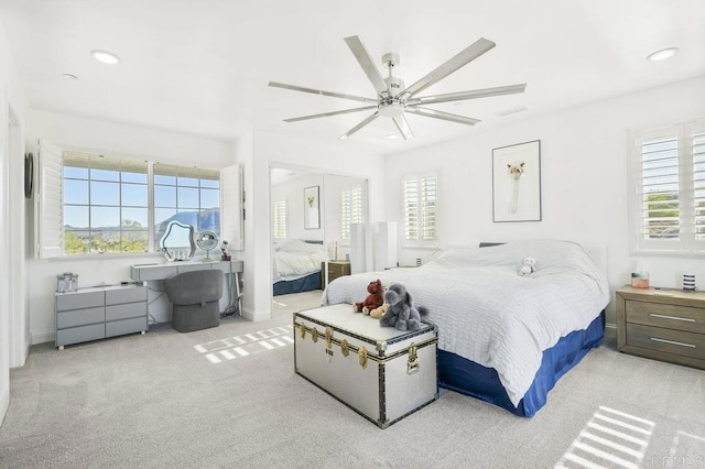 bedroom featuring ceiling fan, light colored carpet, and multiple windows