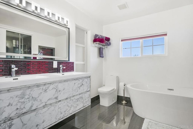 bathroom with tasteful backsplash, vanity, toilet, and a washtub