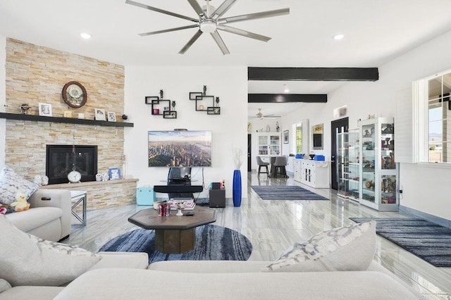 living room featuring ceiling fan, plenty of natural light, beam ceiling, and a fireplace