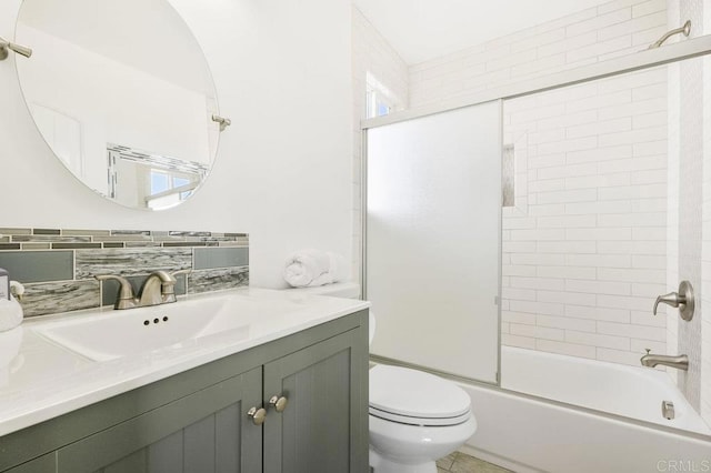 full bathroom featuring shower / bath combination with glass door, vanity, toilet, and tasteful backsplash